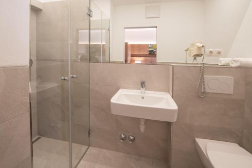 纳莱斯Pension Sandhofer的一间带水槽和玻璃淋浴的浴室