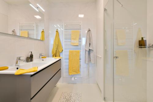 卡德赞德Modern appartement met doorkijk op de duinen的浴室设有水槽和带黄毛巾的淋浴。