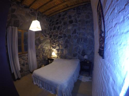 波特雷里约斯UTU TOCO - casa de piedra en lengua Huarpe的一间卧室设有一张床和石墙
