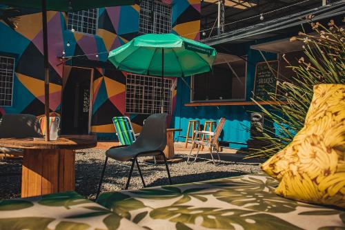 库里提巴Social Hostel Café e Bar的一间带椅子和一张桌子及遮阳伞的房间