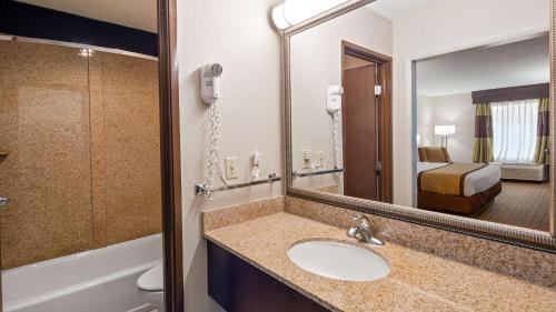 Fayetteville费耶特维尔贝斯特韦斯特酒店的一间带水槽和镜子的浴室以及一张床