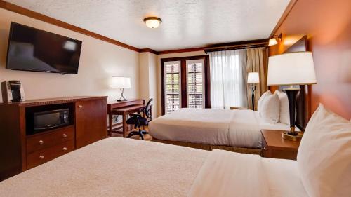 摩押格林威尔贝斯特韦斯特优质酒店的酒店客房设有两张床、一张桌子和一台电视。