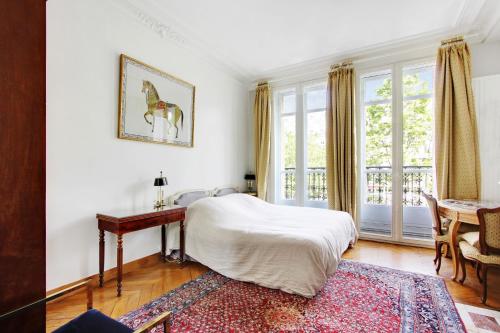 巴黎Suite junior avec balcon et vue sur Arc de Triomphe的一间卧室配有一张床、一张书桌和一个窗户。