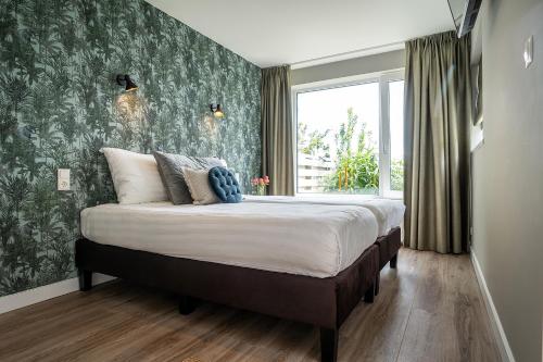 德科克斯多普Hotel het Anker van Texel的一间卧室配有一张带绿色壁纸的大床