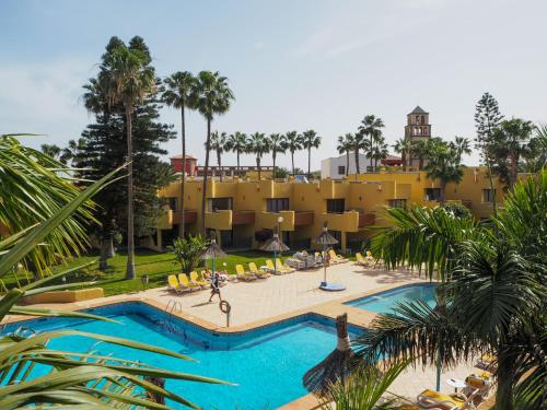 科拉雷侯大西洋花园海滩伴侣公寓的一座带大型游泳池和黄色建筑的度假村