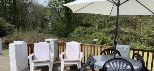 坦伯利Whitestone Cottage的甲板上配有桌椅和遮阳伞