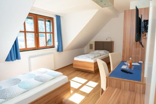 斯皮茨Gästehaus Schütz的客房设有两张床、一张桌子和一张书桌
