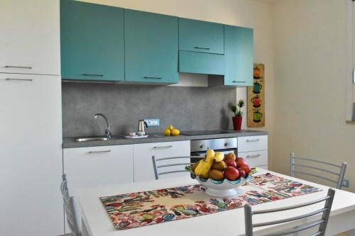 法维尼亚纳Casa Nettuno Favignana的厨房配有蓝色橱柜和一张带一碗水果的桌子