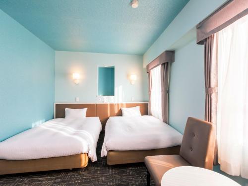 千岁千岁永安国际酒店的一间设有两张床和椅子的房间