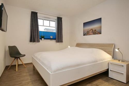 博尔滕哈根Reethaus Am Mariannenweg 04a的卧室配有白色的床和椅子