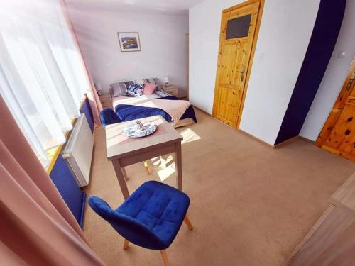 希维拉杜夫-兹德鲁伊Pokoje gościnne "Trudziń-SKI"的配有桌子、蓝色椅子和床的房间