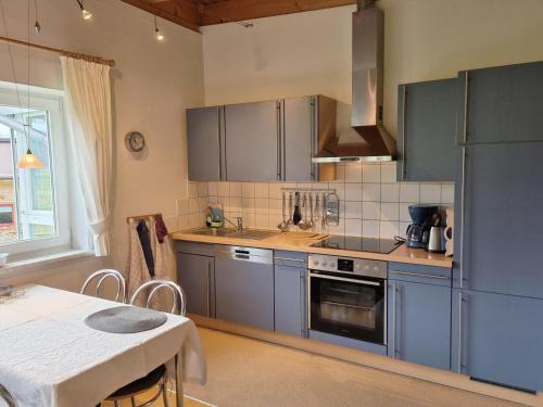 洛伊塔施Appartements Erhol dich gut的厨房配有蓝色橱柜、桌子和桌子。
