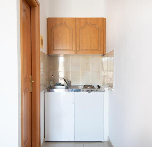 加拉塔斯Poros View的厨房配有白色橱柜和水槽