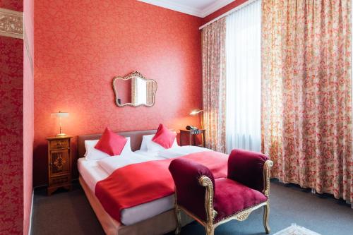 威斯巴登Das Kleine Hotel in ruhiger Stadtlage的红色卧室配有床和椅子