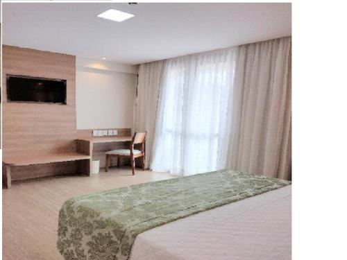 佩德拉阿祖尔Condomínio Vista Azul hotel的一间卧室配有一张床、一张书桌和一个窗户。