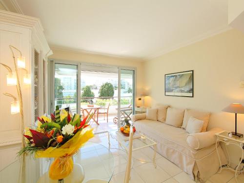 戛纳Apartment Cristal Croisette-1 by Interhome的客厅配有沙发和鲜花桌