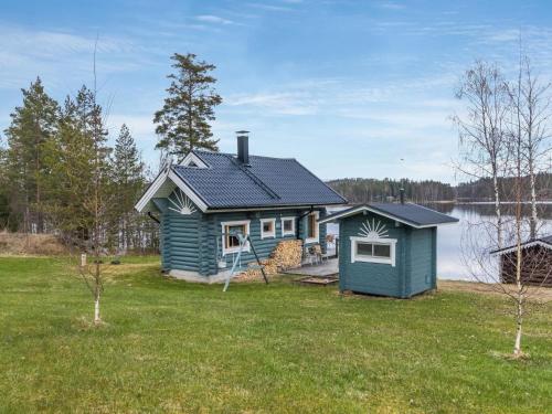 KokkosenlahtiHoliday Home Aurinkotupa by Interhome的湖畔草坪上的蓝色小房子