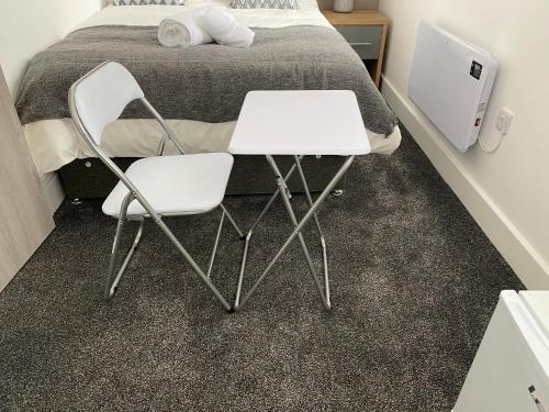韦克菲尔德2D SPV Double En-suite Room的两把白色的椅子和一张桌子(位于床前)