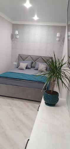 波尔塔瓦Квартира в центре的一间卧室,配有一张床和一张桌子上的盆栽植物
