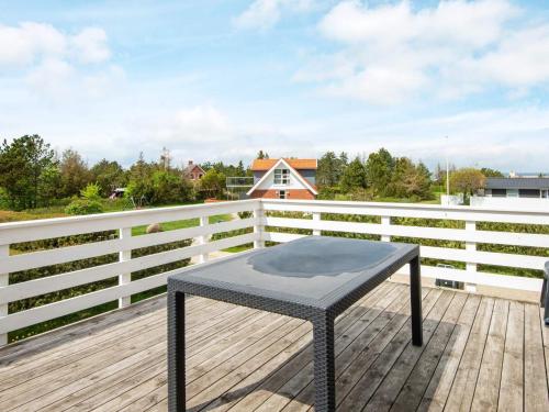 菲耶勒鲁普海滨12 person holiday home in Glesborg的木甲板上的一张黑色桌子和围栏