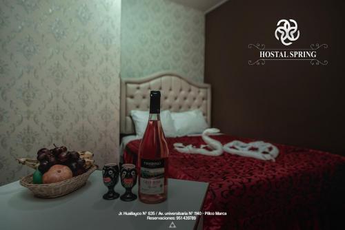 瓦努科Hostal Spring II的床上的一瓶葡萄酒和一篮水果