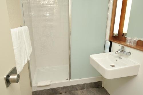 拉贝格钟楼图卢兹南 - 拉贝格因诺普乐酒店的带淋浴和盥洗盆的白色浴室