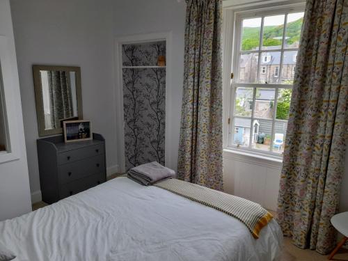 本泰兰Burntisland Garden Apartment, Fife - 40 mins to Edinburgh的一间卧室配有床和带窗帘的窗户