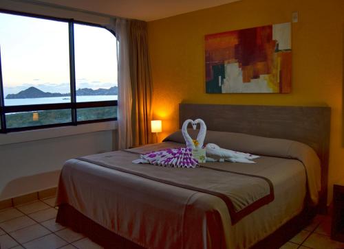 卡波圣卢卡斯Sunrock Hotel & Suites的一间卧室设有一张床和一个大窗户
