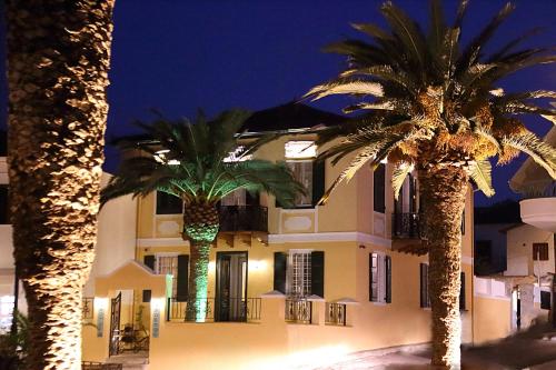 加拉希德松Nostos Hotel的两棵棕榈树在晚上的一座建筑前