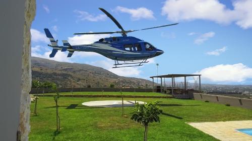 苏达Villa Kedria with a panoramic ocean view的一架蓝色直升机飞越院子