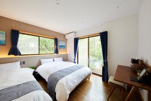 山中湖村湖の辺の宿時翠的一间卧室设有两张床、一张桌子和窗户。