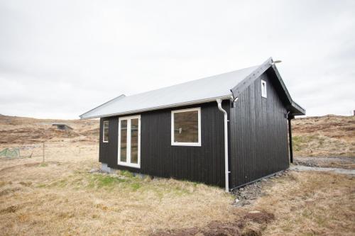 托尔斯港Luxury Cottage in Tórshavn的山丘上带田野的黑色房子