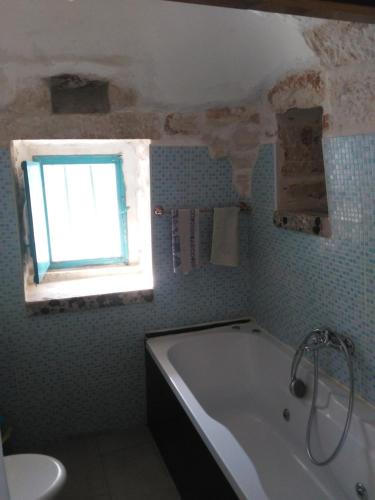 马丁纳弗兰卡Trullo Francisco的带浴缸的浴室和窗户。