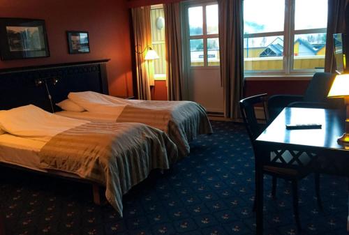 GrongGrong Hotell的酒店客房设有两张床、一张书桌和窗户。