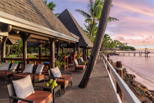 瓦阿Shangri-La Yanuca Island, Fiji的海滩上的餐厅,配有椅子和棕榈树