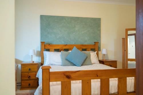 Willunga流连忘返葡萄园公寓的一间卧室配有一张带蓝色枕头的木床。