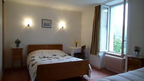 Le Brugeron玫瑰人生酒店的一间卧室设有一张床和一个窗口