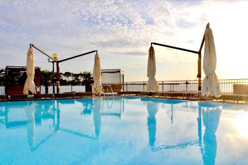 波雷奇BO Hotel Palazzo的一个带白色遮阳伞的大型游泳池