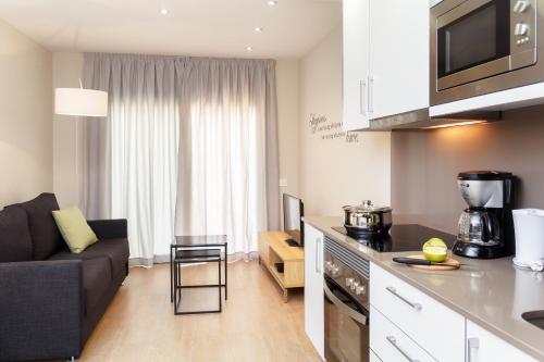 巴塞罗那温馨之家广场公寓酒店的厨房以及带沙发和桌子的客厅。