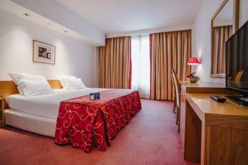 马亚Hotel Premium Porto Maia的配有一张床和一张书桌的酒店客房