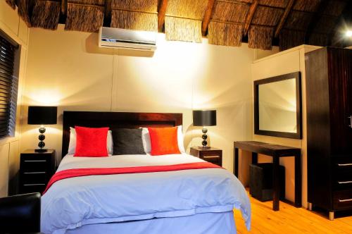 布隆方丹Impa-Lala Country Estate的一间卧室配有一张带红色和橙色枕头的大床