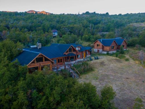 Lago FutalaufquenLaguna Larga Lodge的蓝色屋顶的圆木房屋空中景观