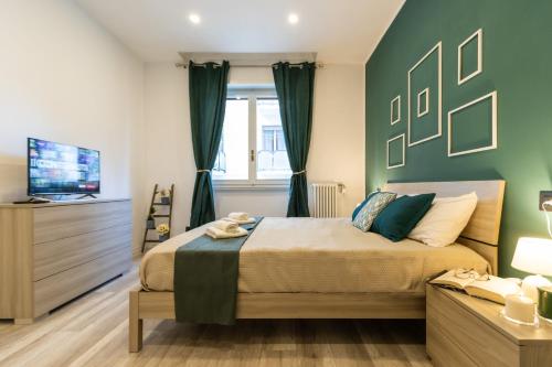 阿罗纳Green Pearl ✰✰✰✰✰ Appartamento a 100 metri dal lago的一间卧室设有一张带绿色墙壁的床和一台电视。