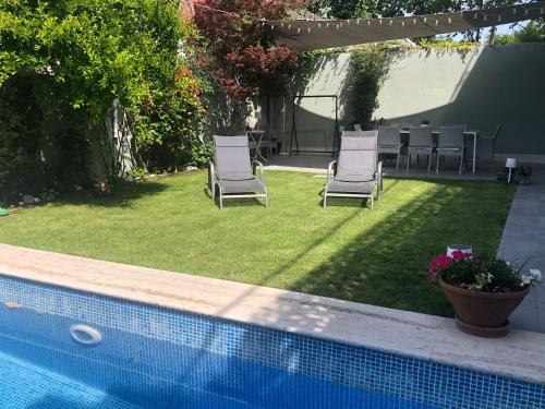 马德里chalet villa inside Madrid的两把椅子和一张桌子以及一个游泳池