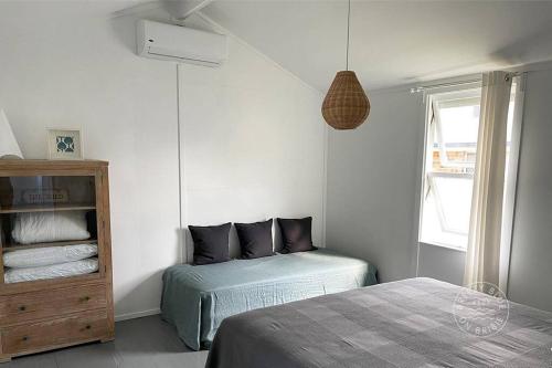 邦加里Breezy Blue on Bribie的一间卧室设有两张床、一个橱柜和一个窗口。