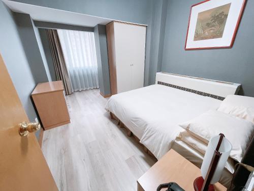 大连大连日航饭店公寓 的一间小卧室,配有两张床和一张桌子