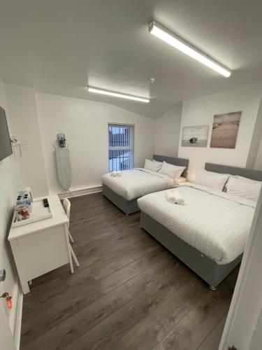利物浦County road rooms的一间卧室设有两张床、一张桌子和一个窗口。