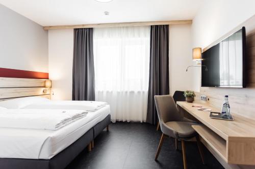 BöheimkirchenHotel Smart Liv'in的配有一张床和一张书桌的酒店客房