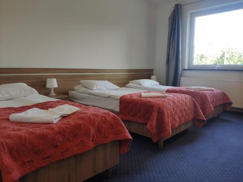 日古夫Hotel Eden的客房设有两张带红色床单的床和窗户。