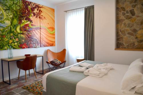塔里法斯罗斯19号套房旅馆的一间卧室配有一张床、一张书桌和一幅画
